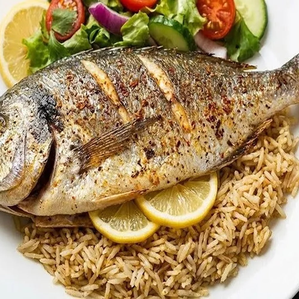 Grilled whole fish served with rice and fresh salad