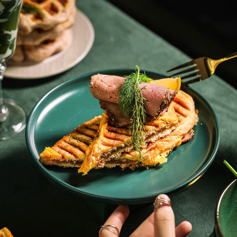 Grilled sandwich topped with roast beef and fresh herbs