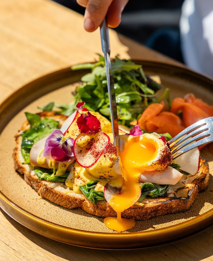Eggs benedict toast topped with fresh vegetables and herbs
